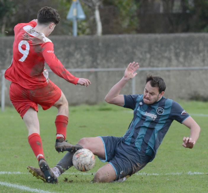 Brennan Devonald puts in a strong tackle for Tish against Milford United